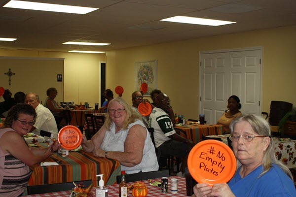 image shows Shepherd's Table diners holding up "no empty plates" signs at dinner